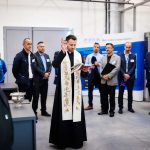 Polska-launch-blessing Priest giving a blessing in front of a group of visitors at Poeton Polska launch